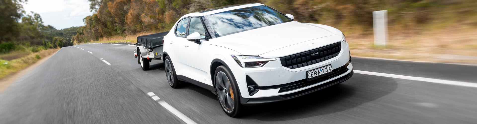 A white Polestar 2 towing a trailer