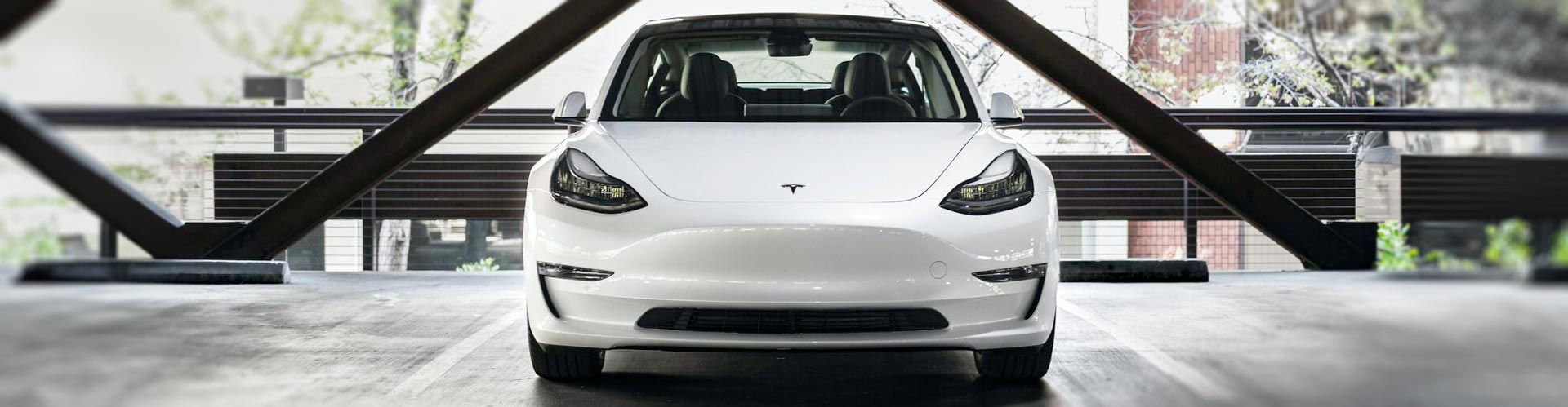 Face on photo of a white tesla parked in a carpark