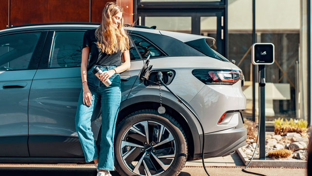 A woman waits while her EV charges