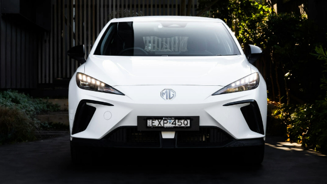 Front view of a white MG4 car parked in a dimly lit driveway.