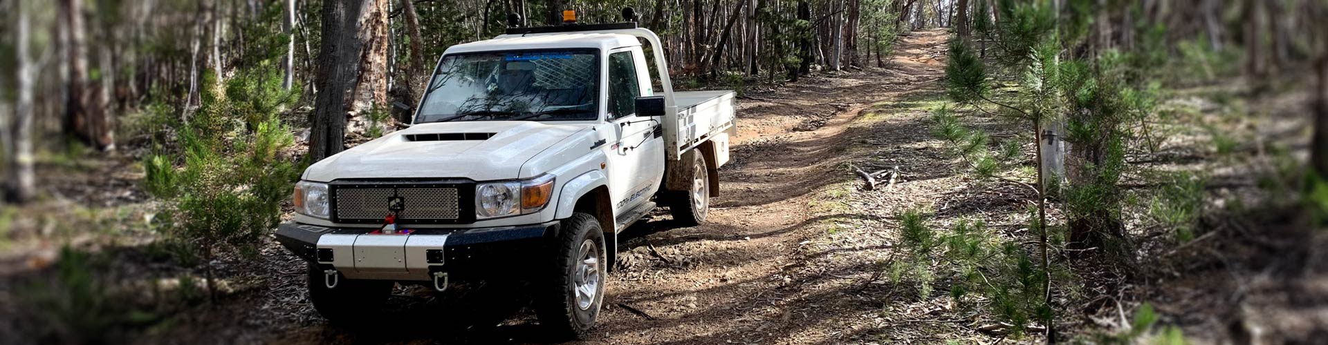 A converted electric Toyota Land Cruiser drives down a bush track