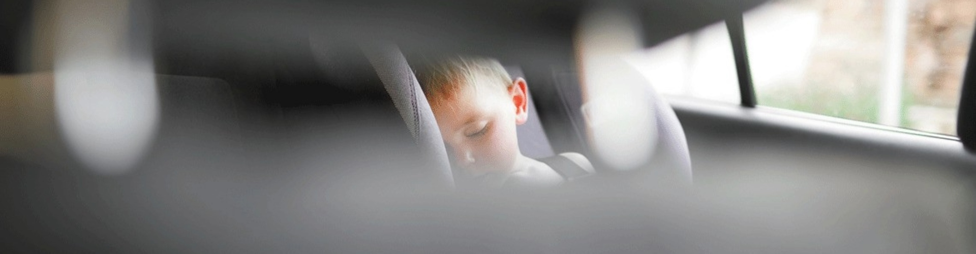 A child sleep in a restrainer in the back seat of a car