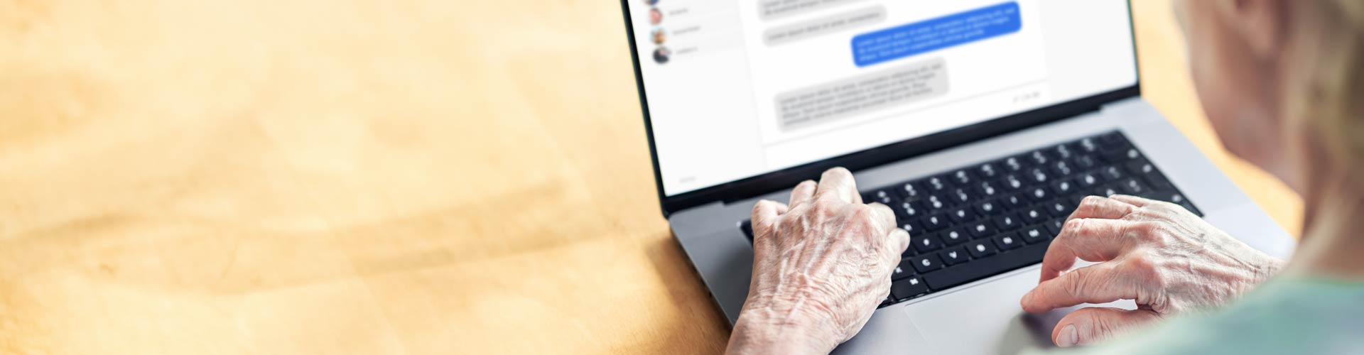 An old woman's hand typing on a laptop keyboard into facebook messenger