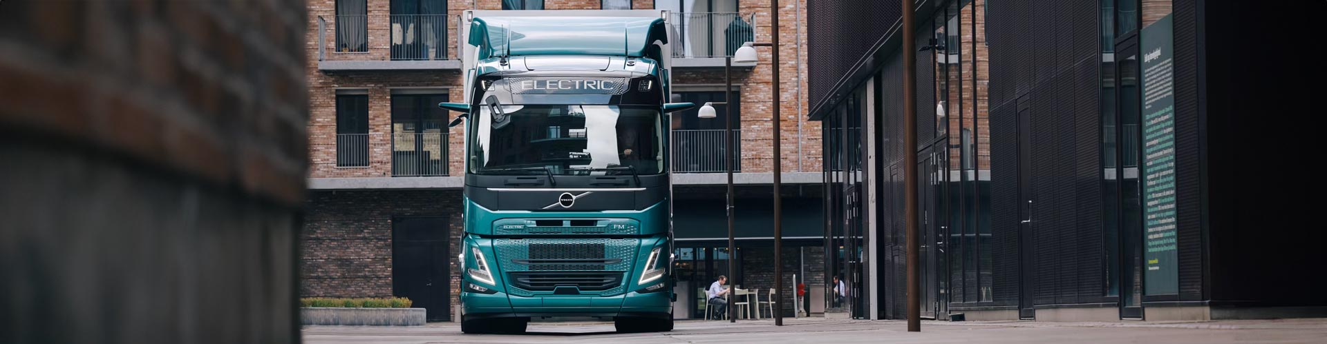 Electric Volvo truck parked in alley in front of a brick building