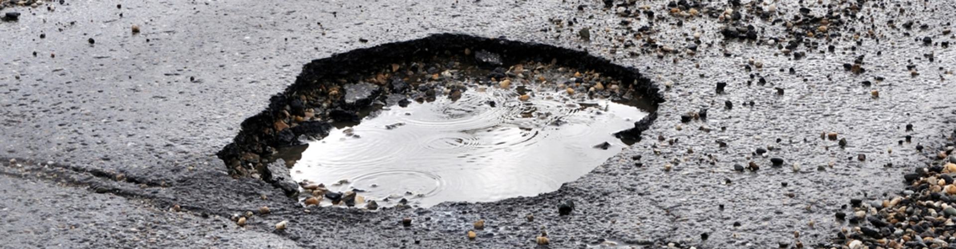 A large pothole full of water in the road