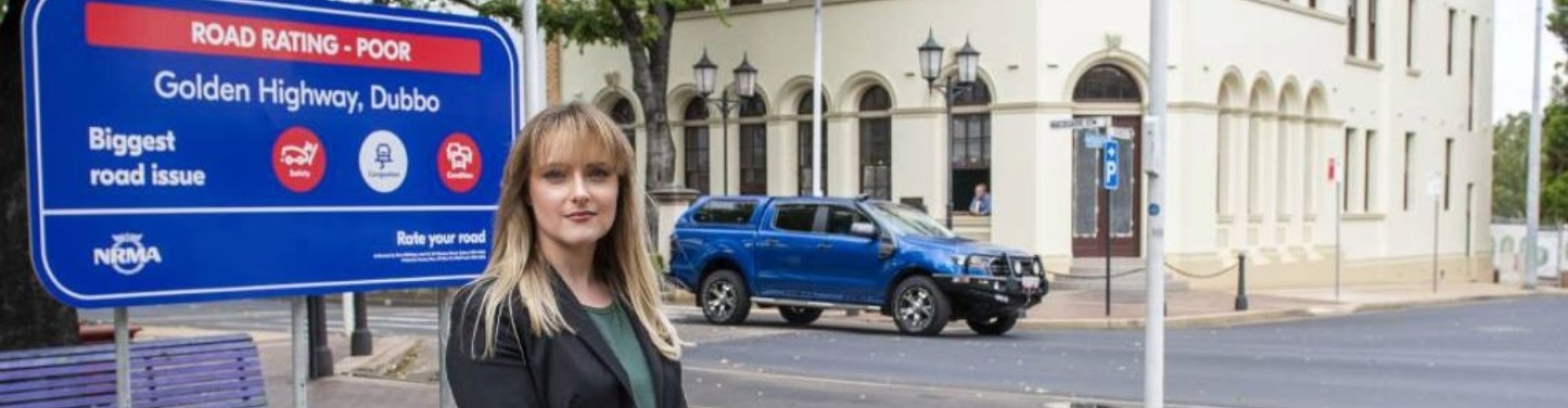 woman wearing business attire standing next to road rating sign