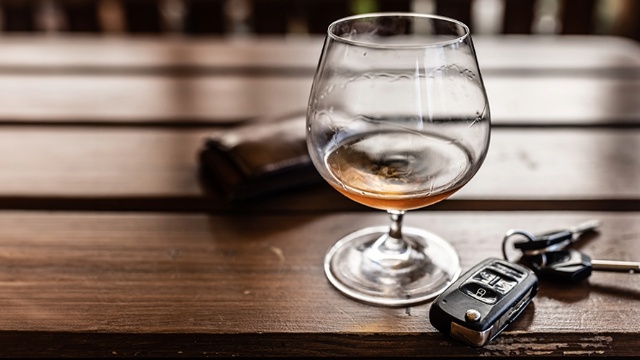 A key fob sits on a table beside a glass of alcohol