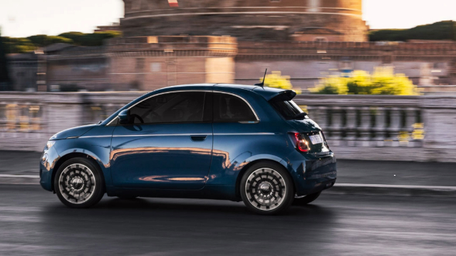 Side view of a blue Fiat 500 driving along a road. 