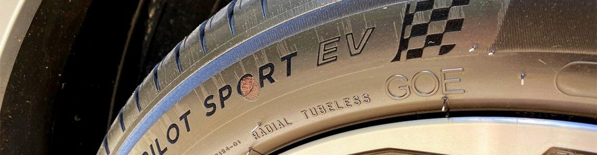 Side view of one electric vehicle tyre and silver wheel.