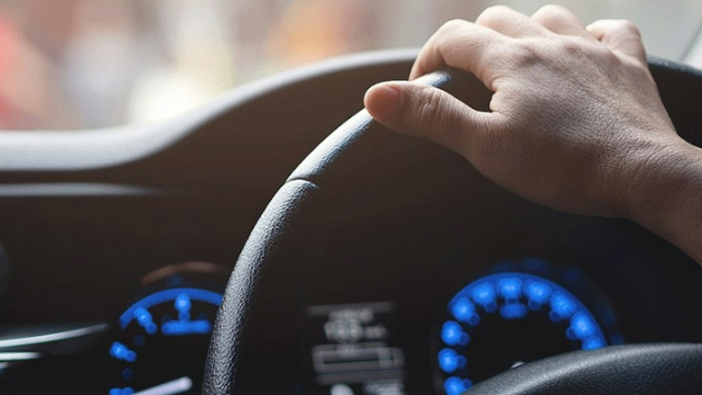 A driver's hand on a steering wheel