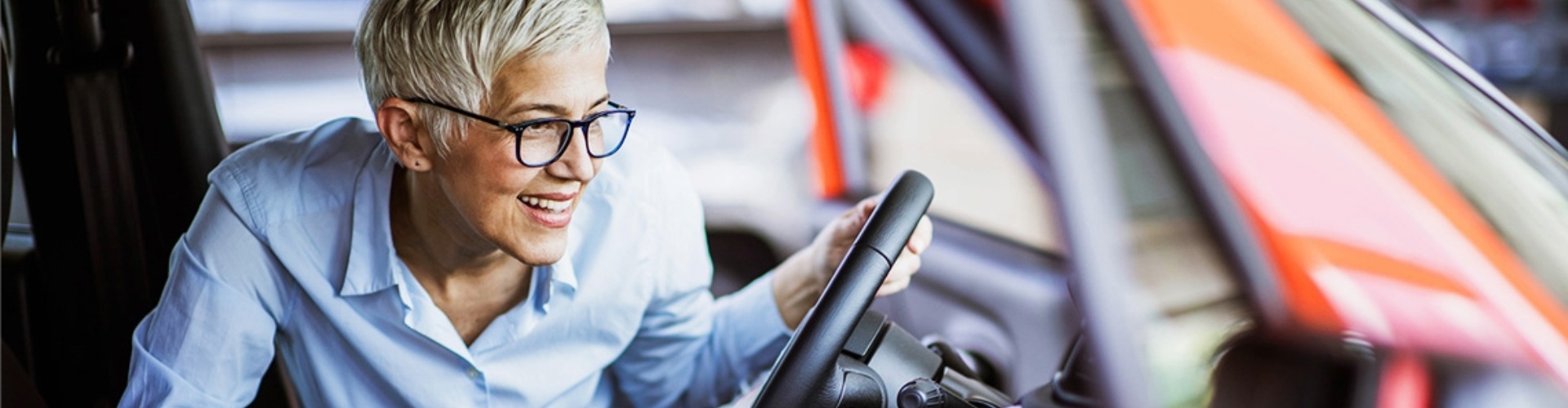 Someone leaning into the cabin of a vehicle to examine the dashboard