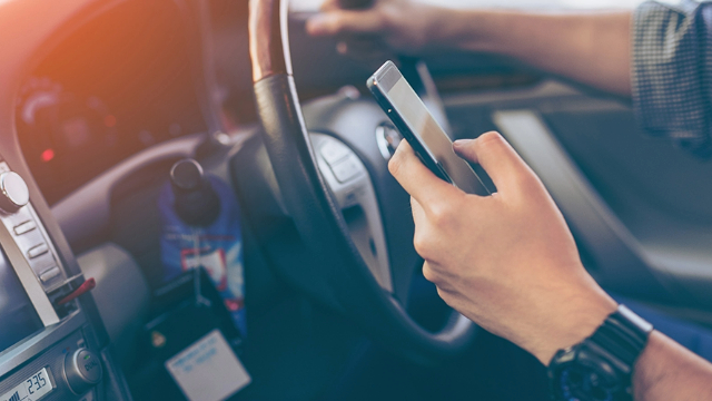 Close-up of a driver's hand using a mobile phone