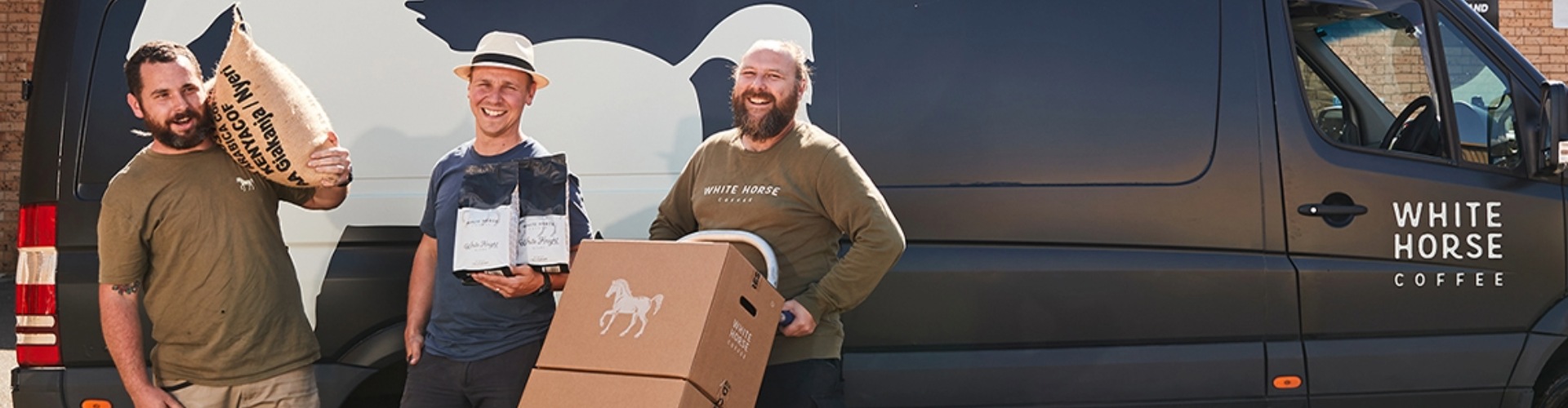 Three of the crew from Whitehorse coffee stand beside one of their delivery vans