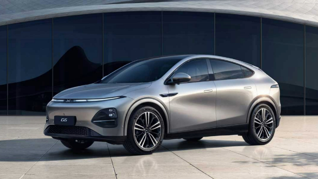 Side-angle view of a silver SUV parked in front of a building with a large glass window.