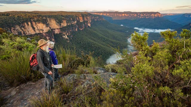 Older couple pause hiking to view Blue Mountains vista