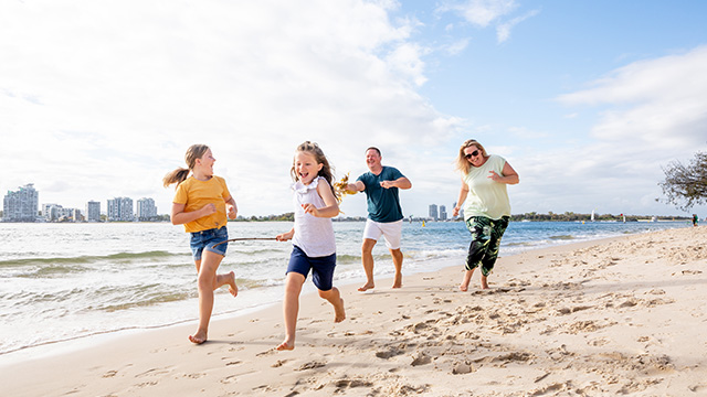 A family of four running on the beach