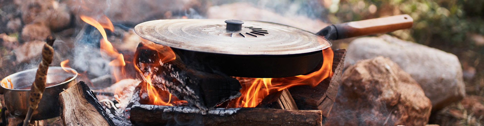 Frying pan with a lid over a campfire