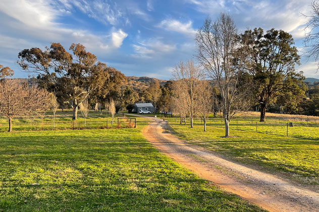 A sunlit lawn sprawls in front of a winter holiday cottage on a crisp morning