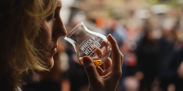 A woman sniffs whiskey from a monogrammed glass