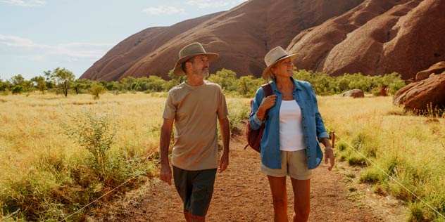 A couple walks around the base of Uluru