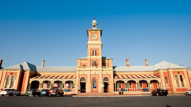 jpg view of the front of red brick and sandstone historic railway station with clock and bell tower