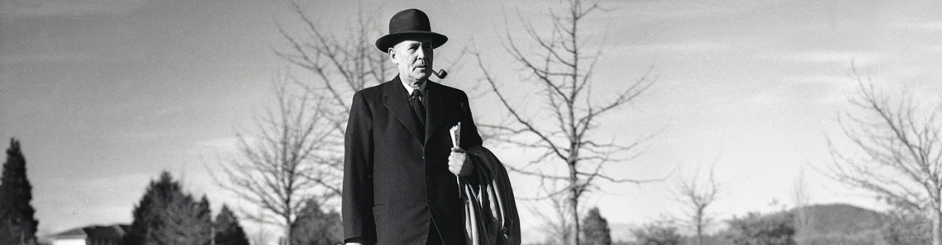 ben-chifley-former-pm-1920x500 A black and white photo of former Prime Minister Ben Chifley, in his sixties, wearing a hat and smoking a pipe, walking down a sidewalk.