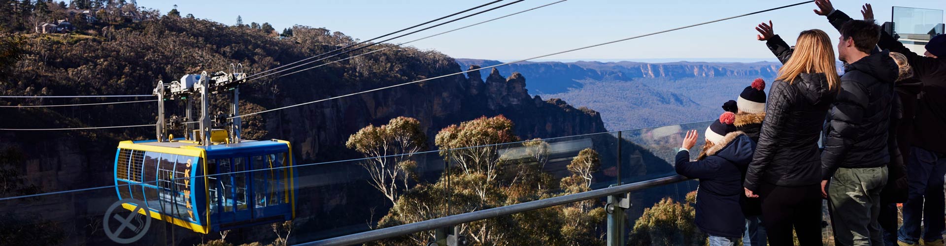 A family waves at a cable car in the Blue Mountains