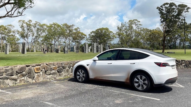 white tesla parked near Glen Innes celtic standing stones