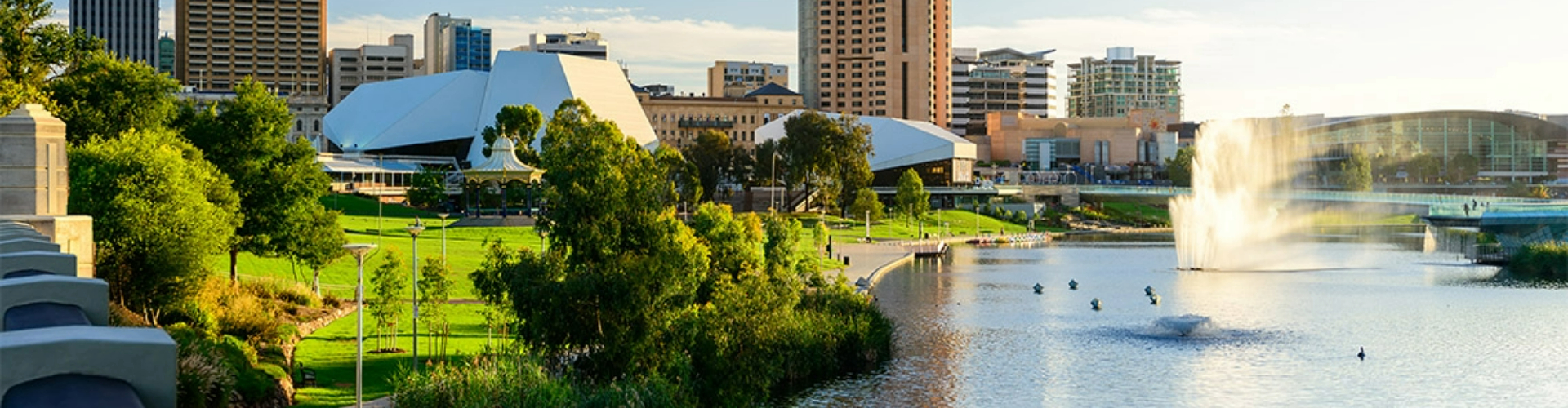 festival-centre-adelaide-sa-1920x500 Three large white, not quite rectangular buildings in a sunny, manicured park along Adelaide city's riverside.
