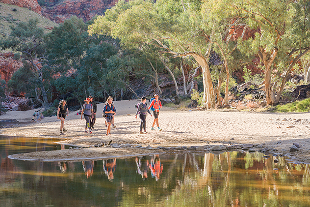 A group of people walking next to a creek