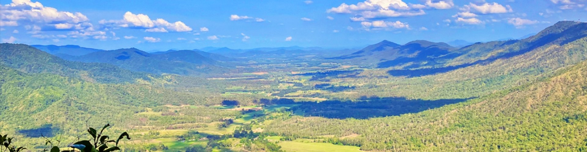 Issac region QLD landscape valley daytime view down into valley with paddocks and tree-covered slopes on a sunny day
