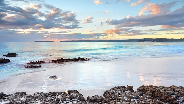 early evening view of jervis bay with volcanic rocks on the shore and white sand
