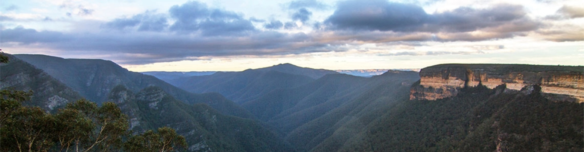 Kanangra-Boyd National Park Jenolan NSW mountain top view through a deep, tree covered valley topped by a sandstone rockface