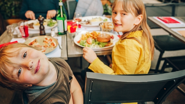 family enjoying a meal together with focus on two young children who are looking at the camera