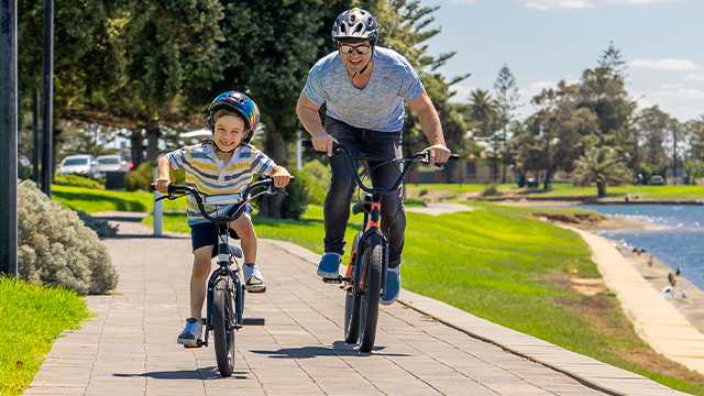 Dad and son ride bikes along the water