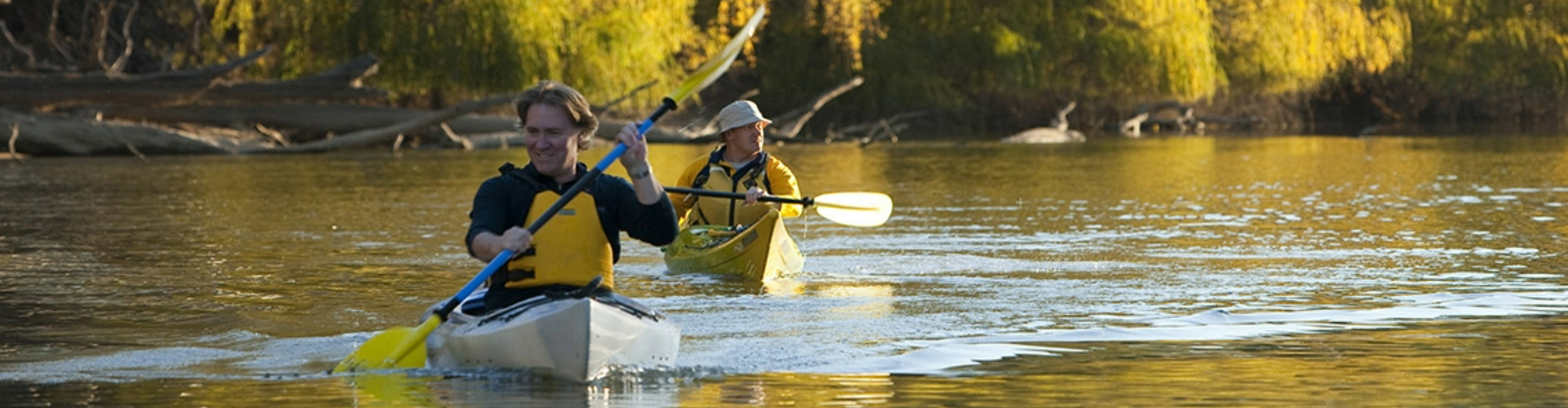 men-kayaking-murray-river-vic-1920x500 Two men kayaking along a sunny, mangrove and tree-lined riverbank.
