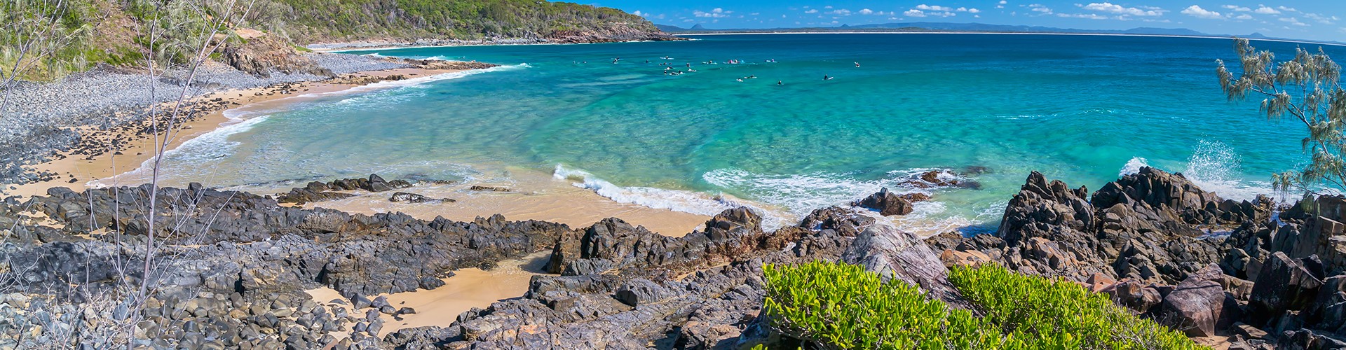 noosa-national-park-beach-1920x500 A rocky, sandy surf beach, with a forested shoreline, beside the Coast Track in Noosa National Park.