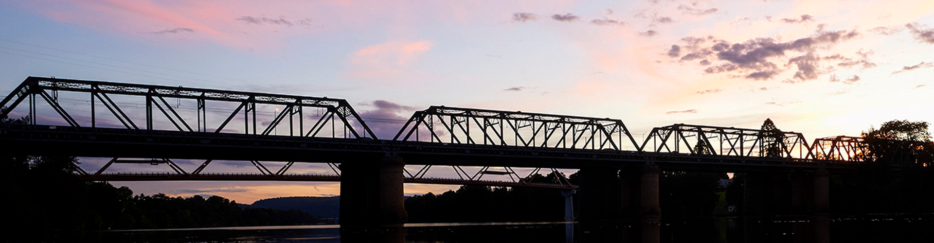A bridge silhouetted in front of a pink and purple sunset