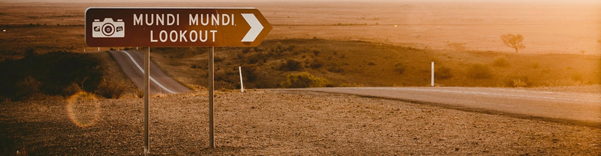 Mundi Mundi lookout sign Silverton NSW signpost saying mundi mundi lookout at the side of country road undulating through flat pastureland