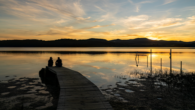 Two people watching the sunset over Merimbula Boardwalk