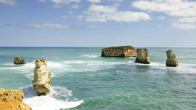 View from the cliffs along Great Ocean Road out at four of the Twelve Apostle rock formations in the sea below.