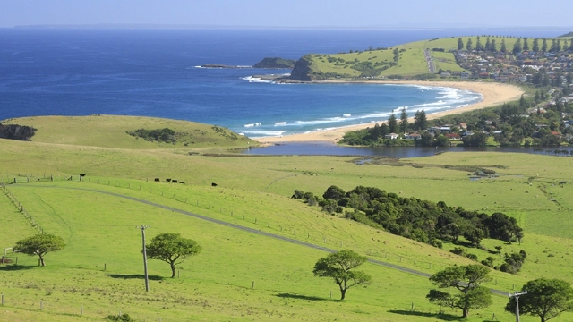 view of fenced paddocks with beach, headland and sea in the distance