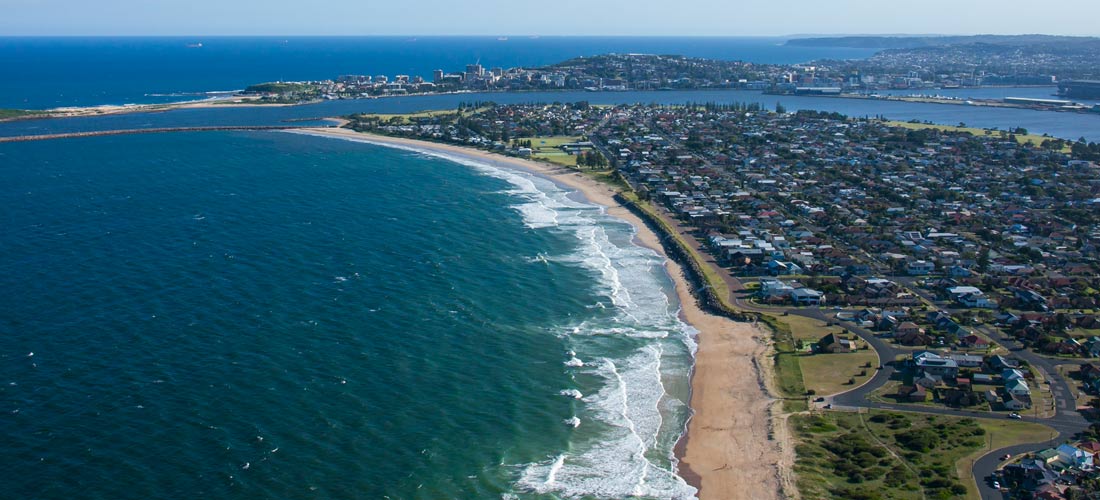 Coastal aerial of the southern end of Stockton Beach and Newcastle City. Destination NSW copyright.