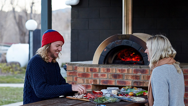 Couple eating by pizza oven Jindabyne Holiday Park NSW my nrma local guides