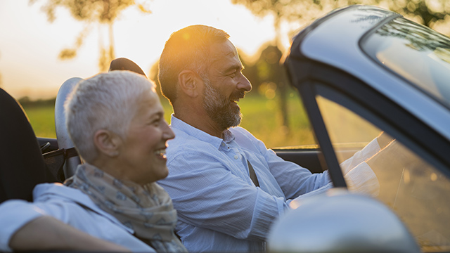 Elderly couple driving in a convertible vehicle