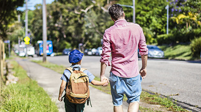 school boy walking with father near school zone