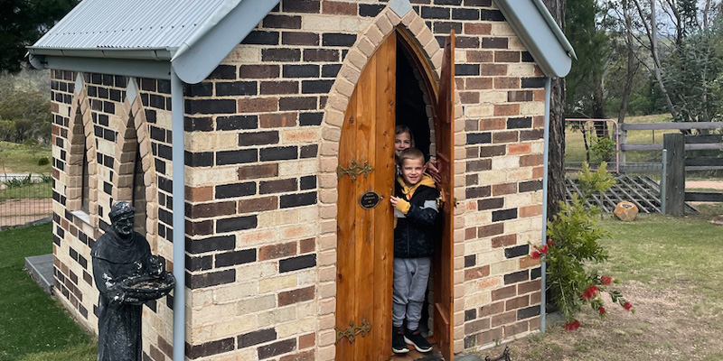 kids peeking out the door of a tiny church