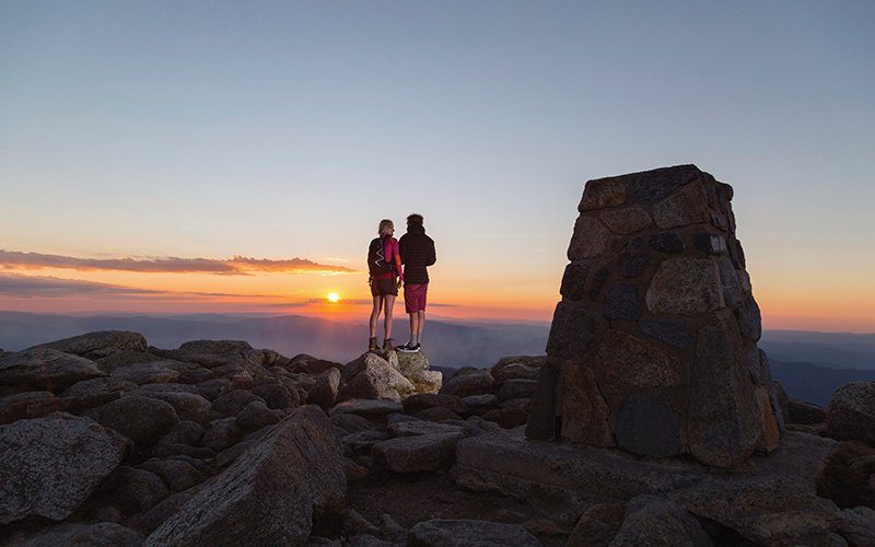 Couple watching the sun set at the summit of Mount Kosciusko in Kosciuszko National Park