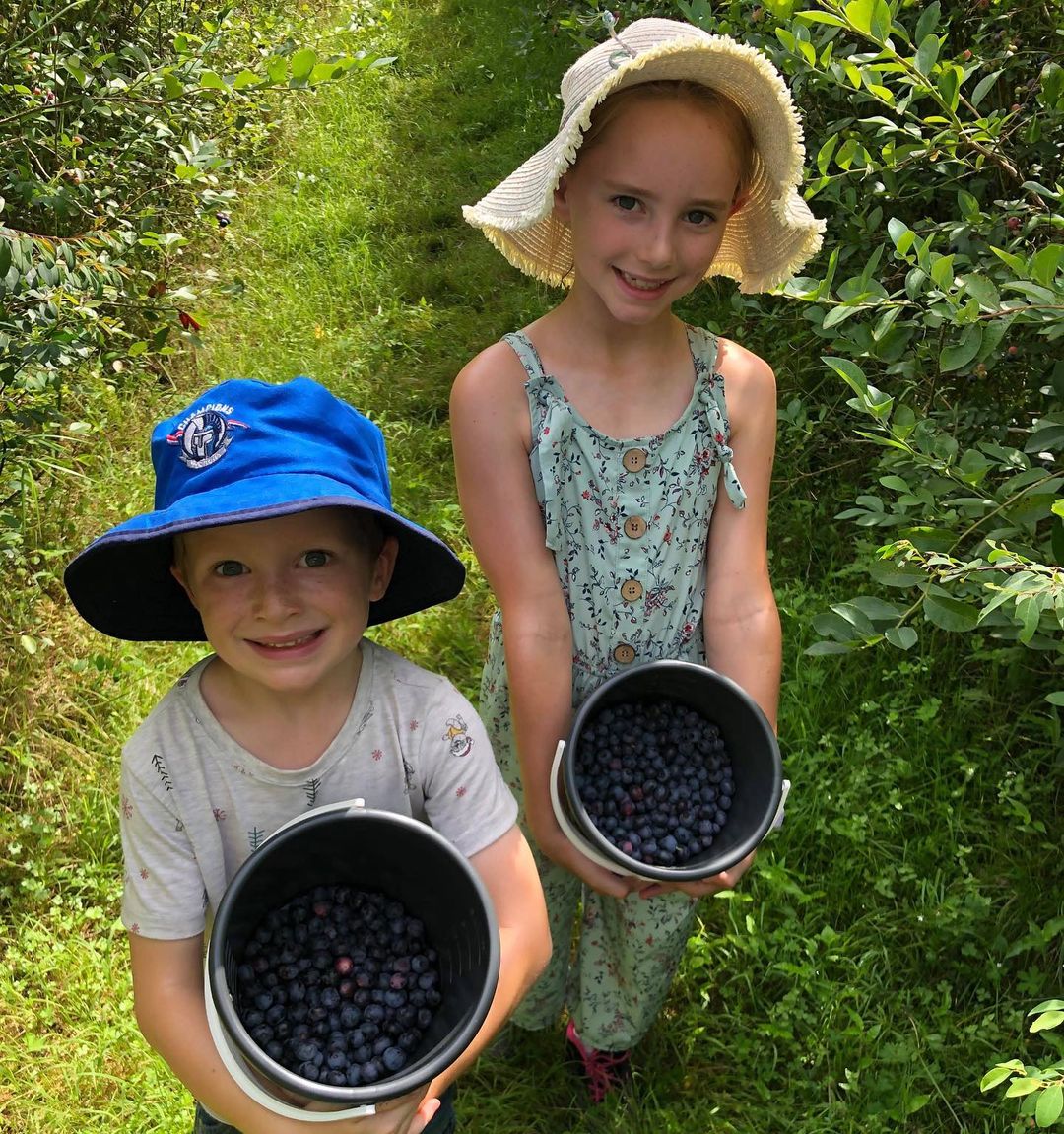 two children each holding a bucket of blueberries