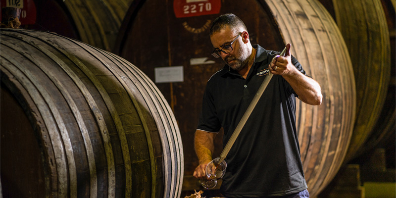 man pouring wine into glass from barrel